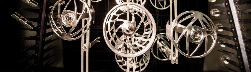 A hanging display of silver fly reel blanks.