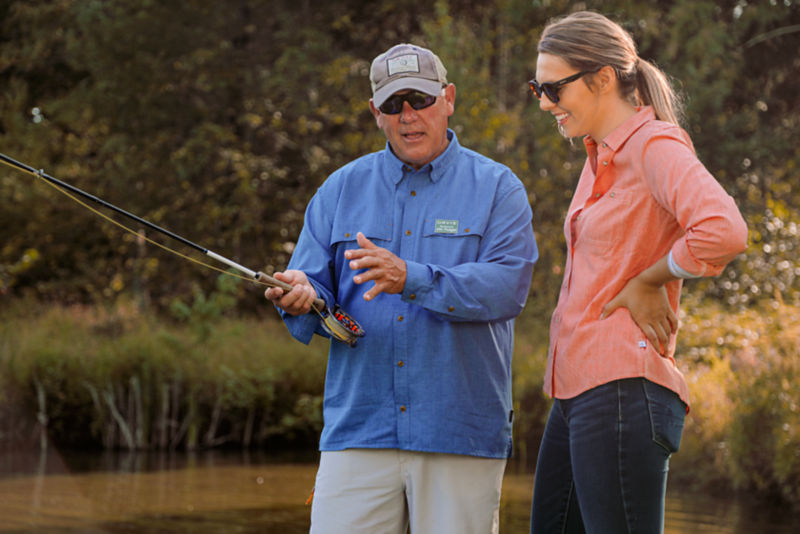 A fly fishing instructor guides a student in proper technique