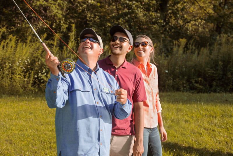 Three people in a fly fishing casting lesson.