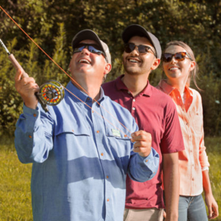 Three people learning how to cast with a fly rod