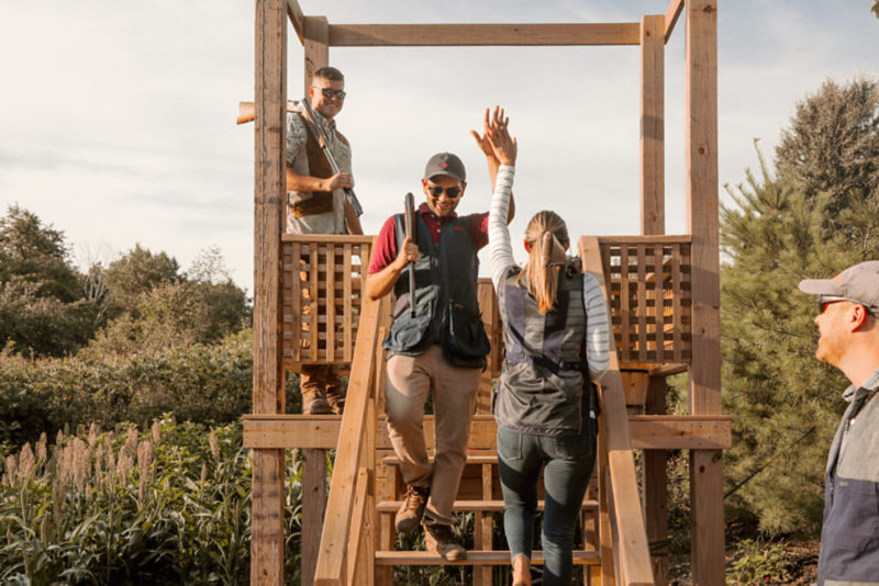 A man high fives a woman while stepping down from a shooting stand.