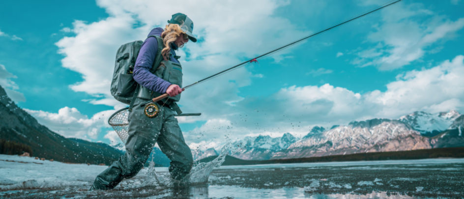 An angler wades in a mountain lake in Alberta, Canada.