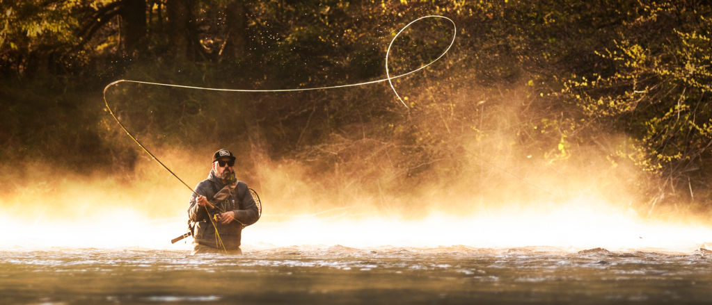 Man casting a spey rod hip-deep in a river
