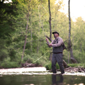 Angler with a spey rod casts in the middle of a river.
