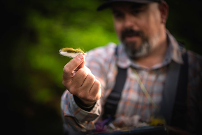 Man holding a fuzzy fly fishing streamer.