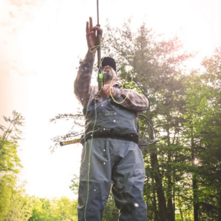 Yellow fly line coming off a rod as an angler in waders casts