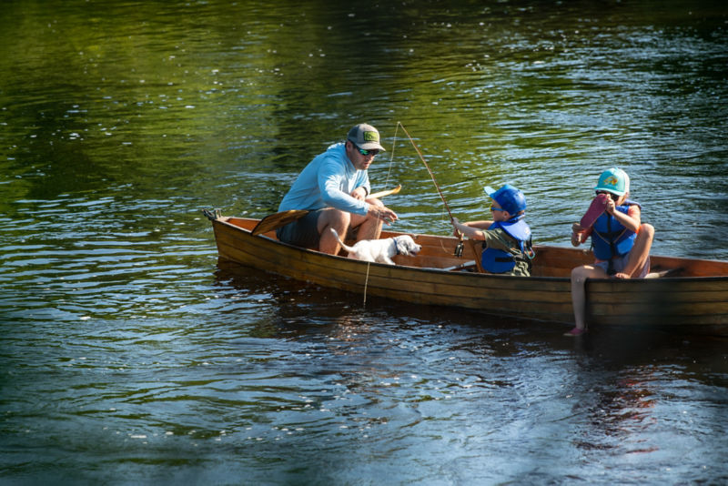 The CEO of Orvis, Simon Perkins teaches his small son the finer points of fly fishing in a wooden canoe.