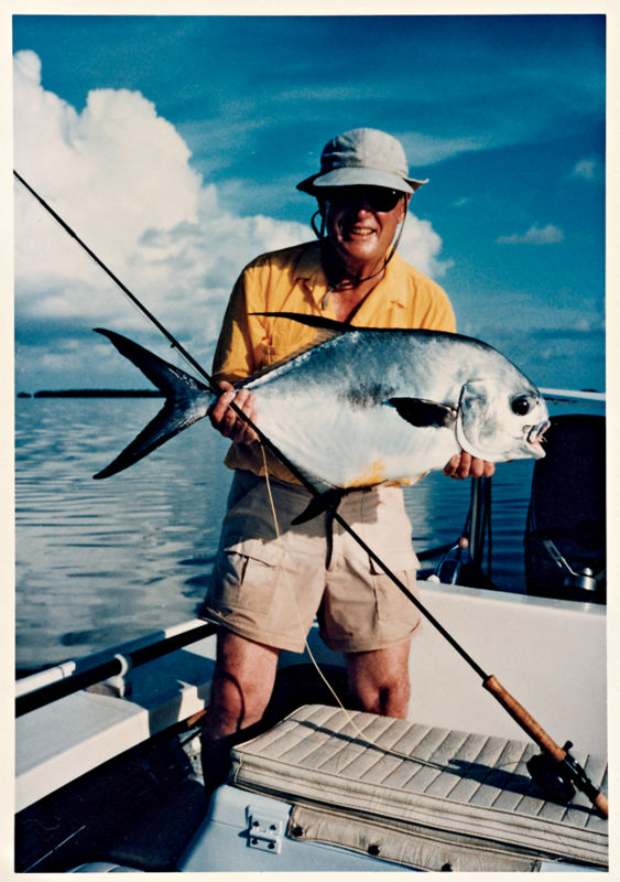 Leigh H Perkins stands in the ocean holding a very large fish.