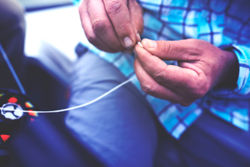 Close-up of hands tying a knot on the end of fishing line.