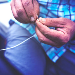 Close-up of hands tying a knot on the end of fishing line.