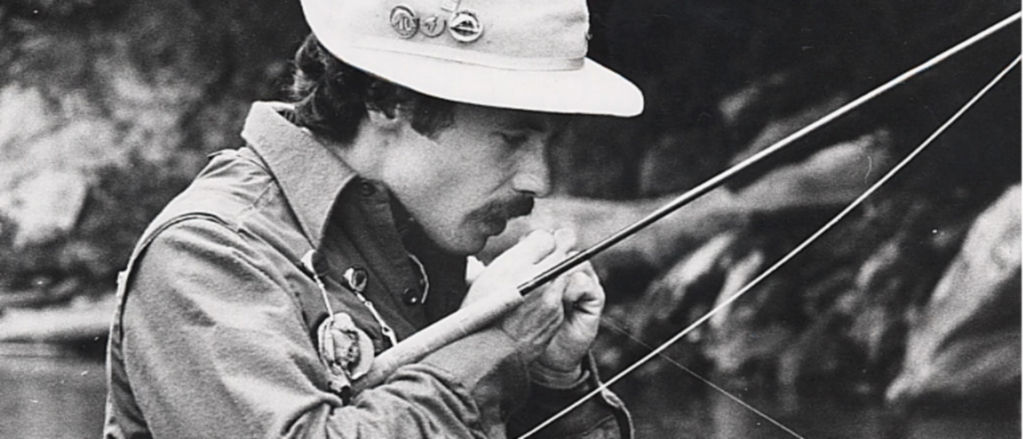 A black and white photo of Perk Perkins tying a fly onto fly line.