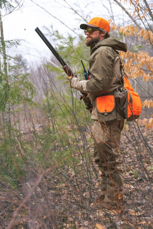 A hunter walks through tall grass wearing a PRO LT hunting vest.