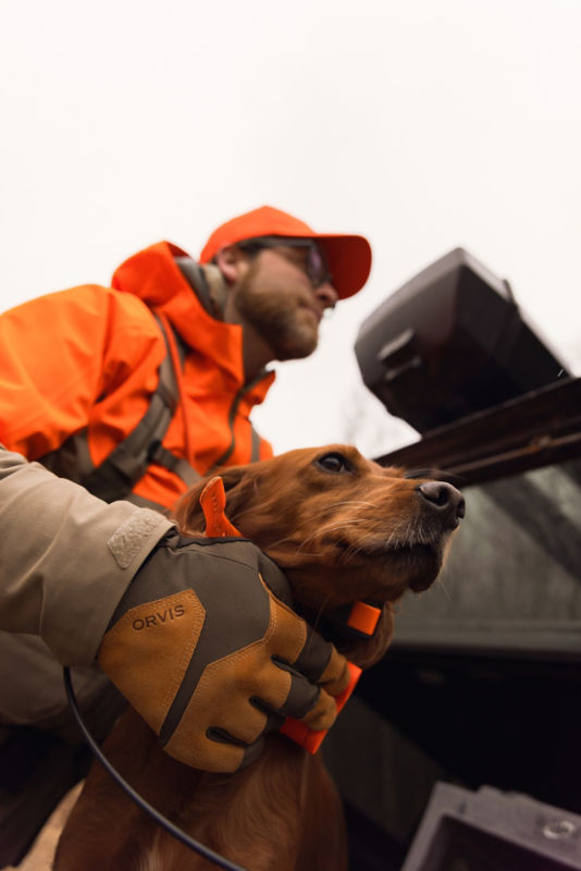A hunter gives his dog a pet.