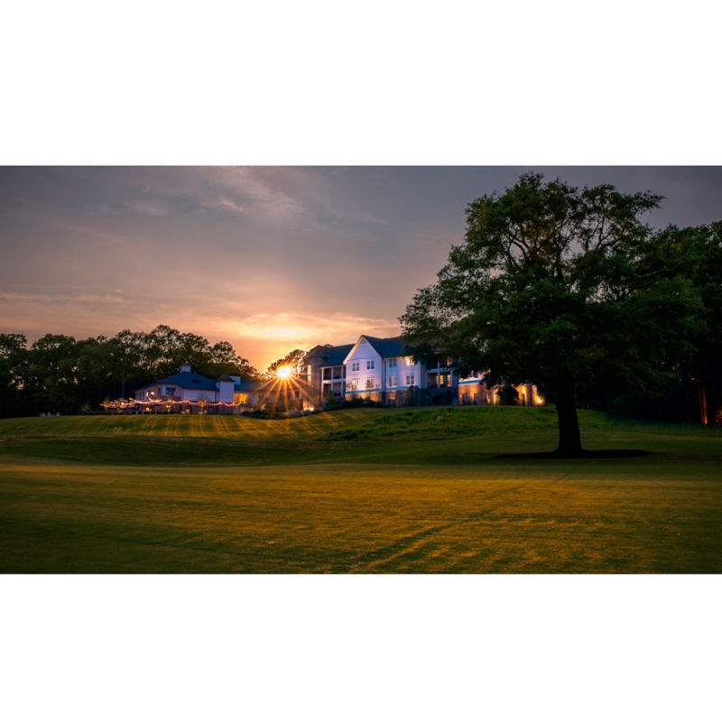 A beautiful sunset shot of a large, white building nestled in trees on a hillside