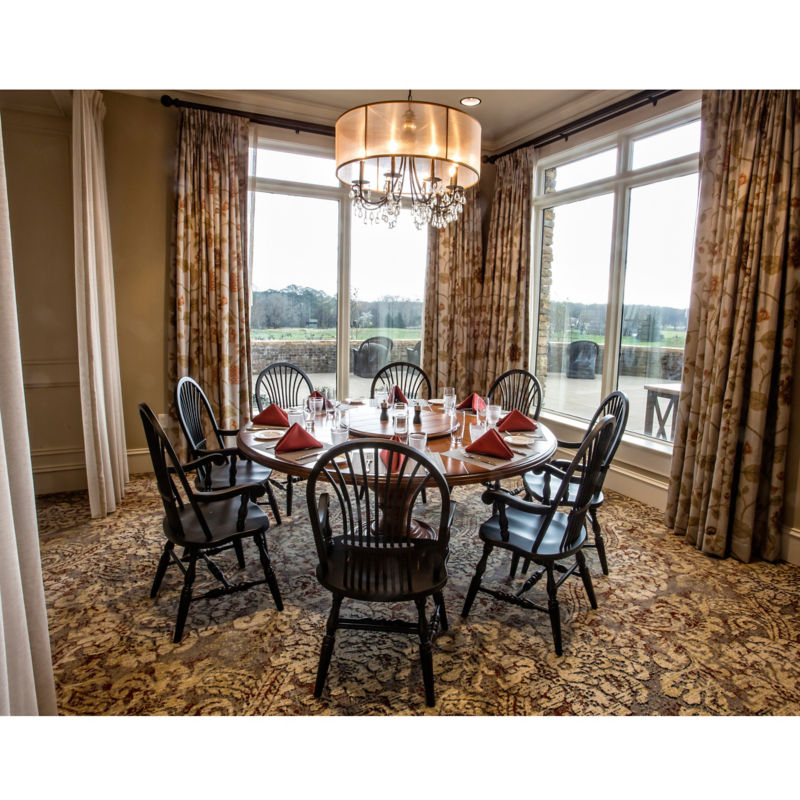 A dining room corner with giant windows and a round table set for a meal