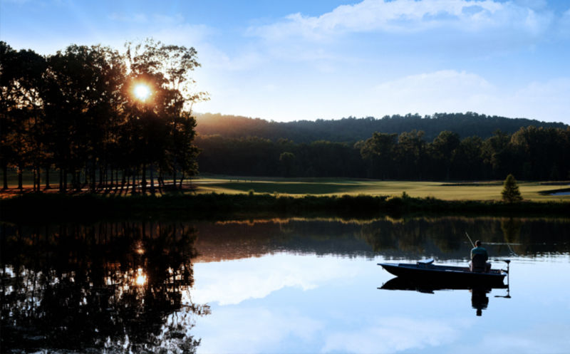 A johnboat with an angler on a lake at sunset