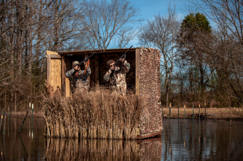 Two hunters standing in a floating duck blind on the water