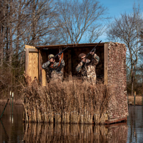 Two hunters standing in a floating duck blind on the water