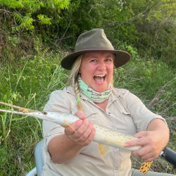 Rebecca Jones smiles widely while showing off a caught fish