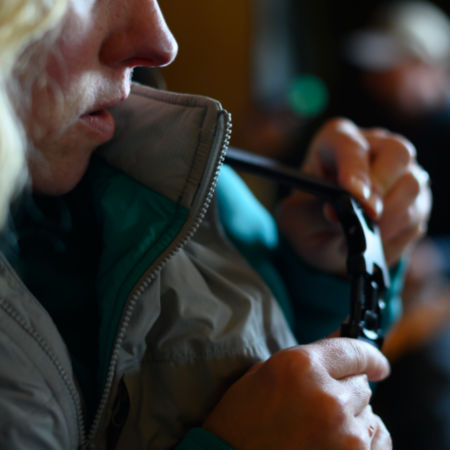 A woman tends to the strap of her waders.