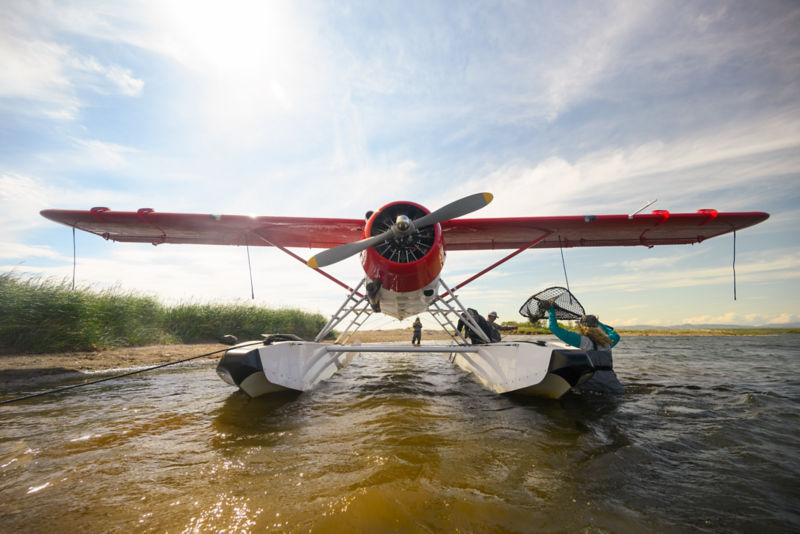 A red and white float plane being loaded with fly fishing gear.
