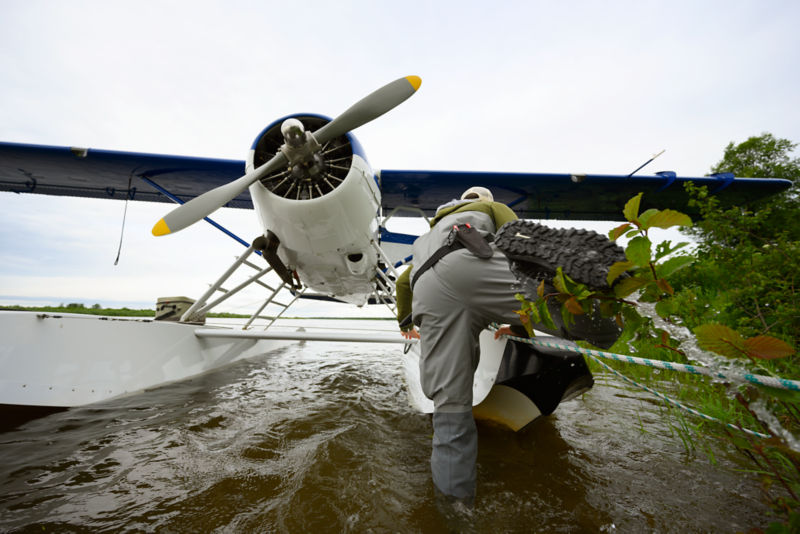 An angler in Orvis Waders climbs onto the pontoon of a sea plane.