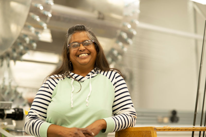 A woman smiling in front of large, cylindrical fly rod-dryers