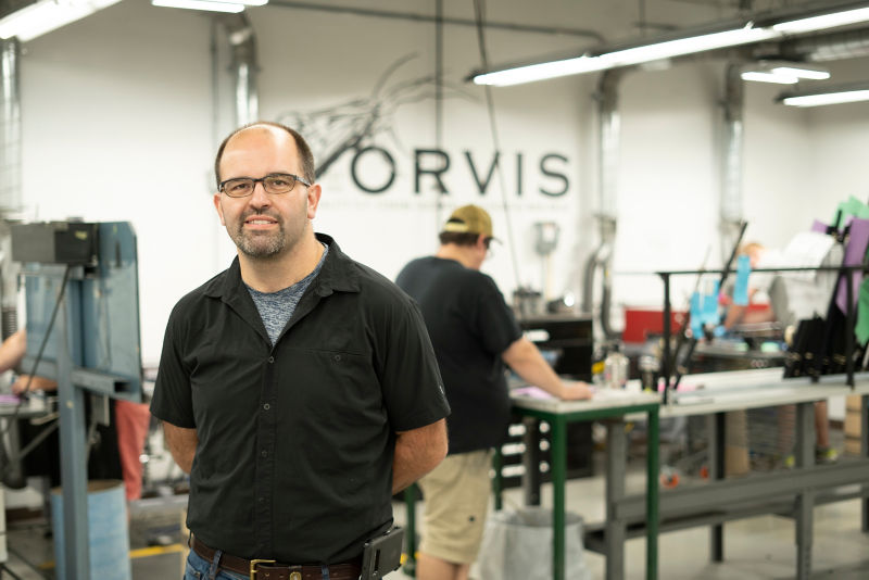 A man in a black shirts standing in a brightly lit workshop
