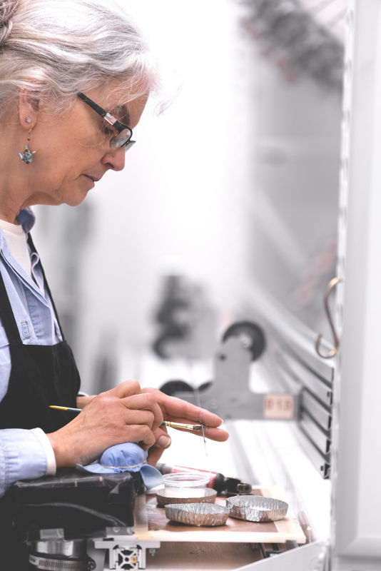 A rod shop builder adds a coating to a fly rod tip.