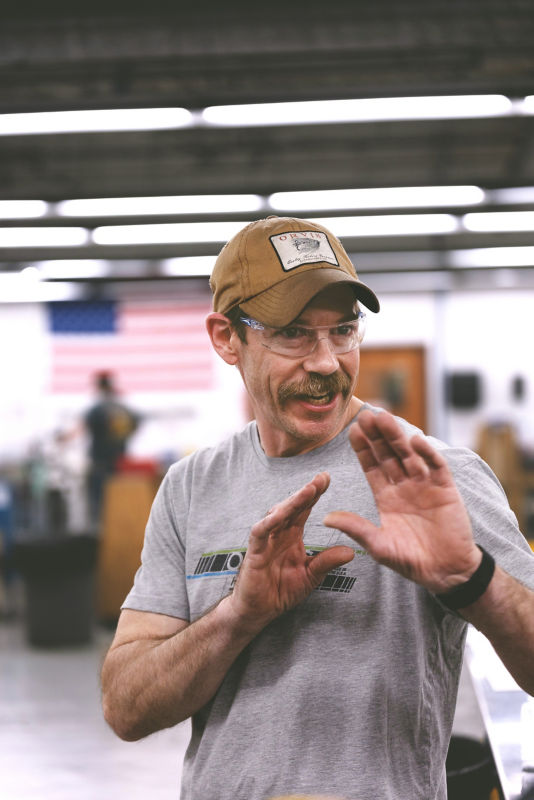 A rod shop builder gestures while explaining to the photographer