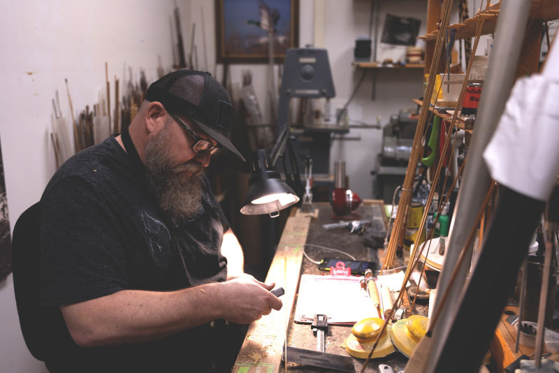 A fly rod engineer tests a part at his work table.