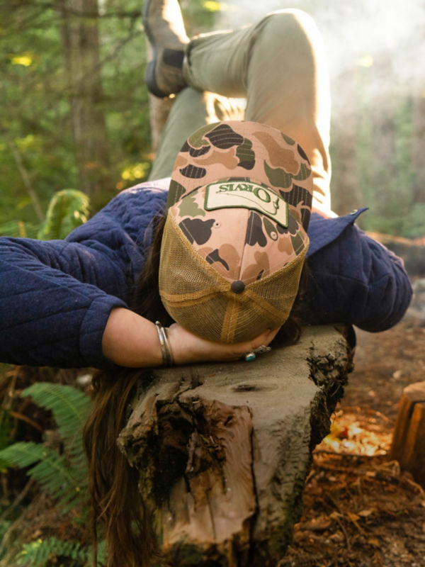 Woman laying on log in the woods.