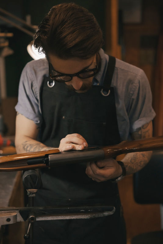 A person carefully inspects a shotgun to be cleaned.