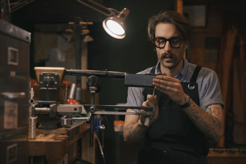 A gunsmith works on part of a shotgun.