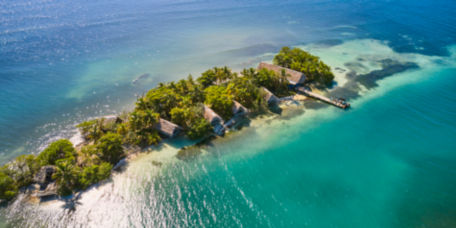 A view from the air of primitive lodge buildings along a snorkeling site on the Belize Barrier Reef.