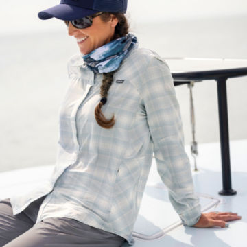 Woman in PRO stretch shirt leans back on skiff.