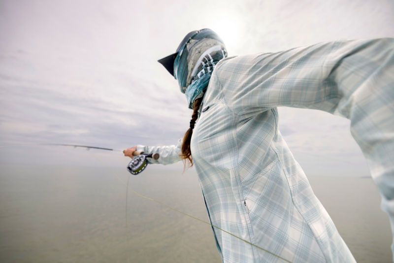 An angler in buff and cap casts from a boat.