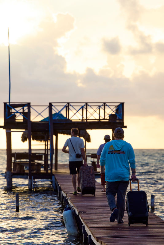 A group of men rolling luggage down a dock toward water