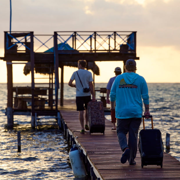 A group of men rolling luggage down a dock toward water