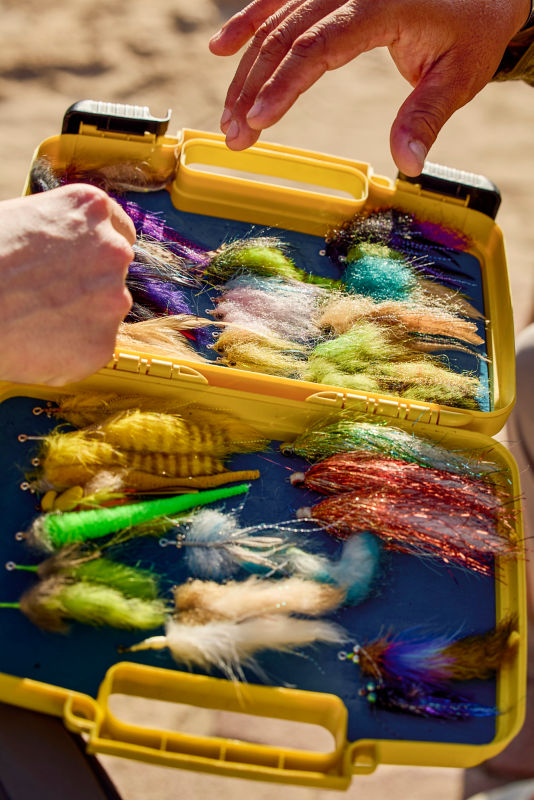 Anglers reach into a fly box.