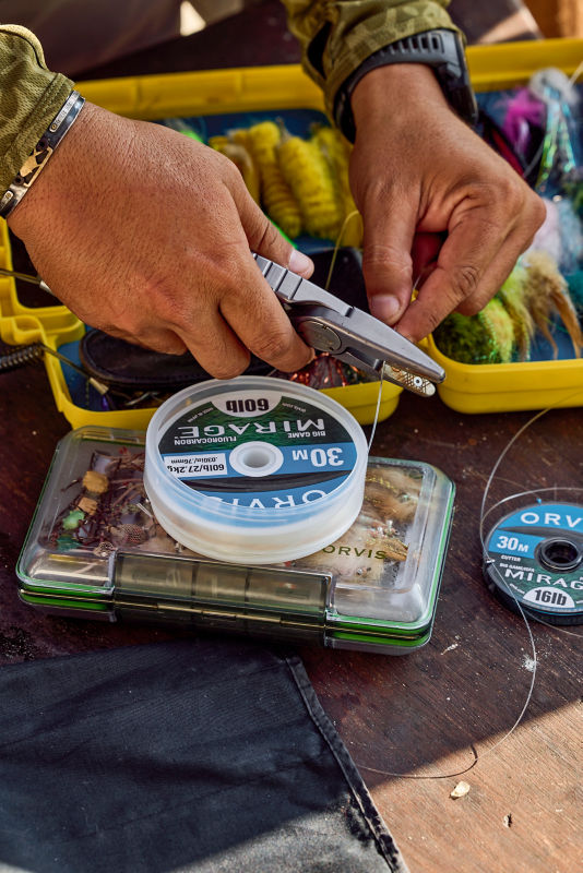 An angler cuts tippet as he ties flies.