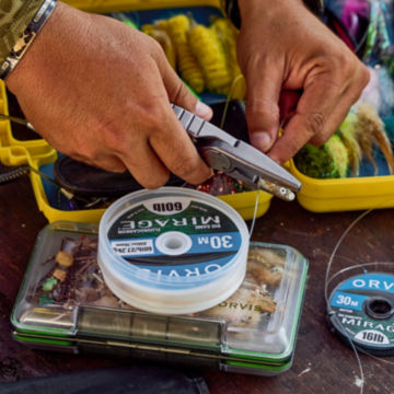 A man snipping line as he adjusts his fly box.