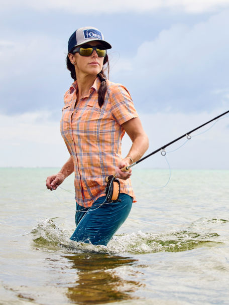 Woman in Sunset Plaid River Guide Shirt handles her fly rod in the surf.