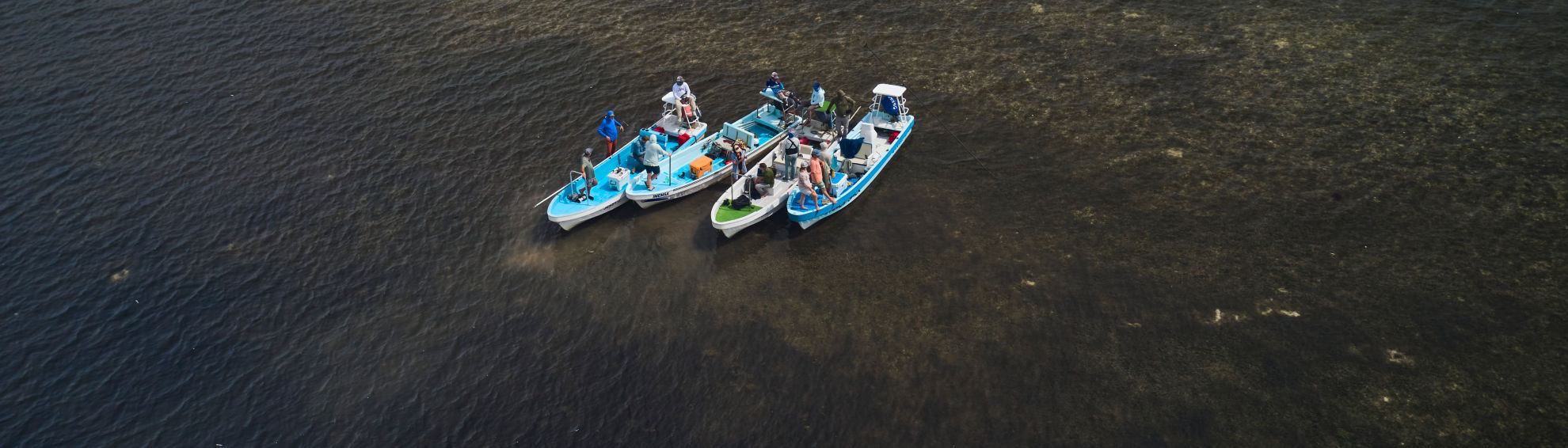 A drone view of 4 boats gathered together in the ocean