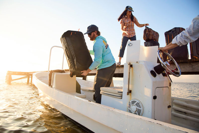 A man and woman loading Trekkage bags onto a boat