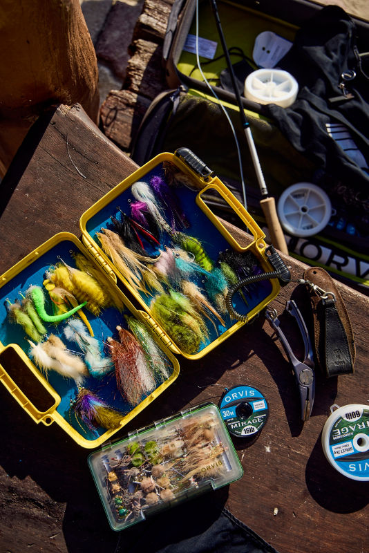 Looking down on a fly box and other fishing supplies.