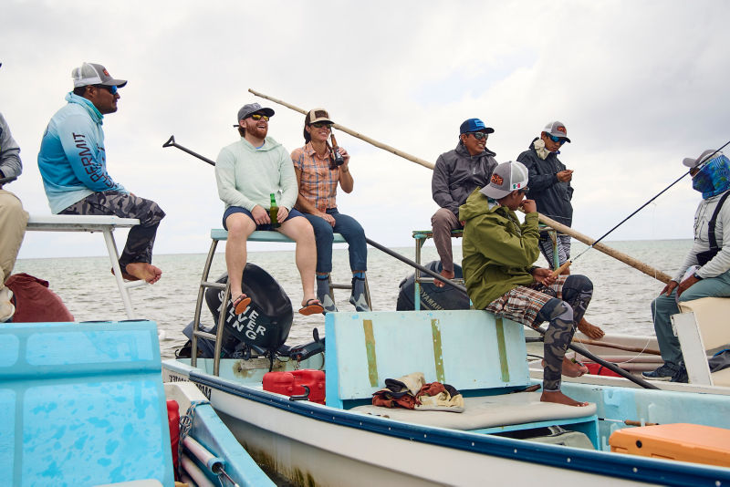 A group of people socializing while sitting on fishing boats in the ocean.