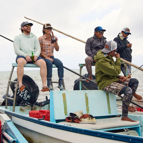 A group of people socializing while sitting on fishing boats in the ocean.
