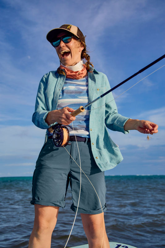 A woman laughs as she casts her rod from the skiff.