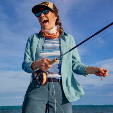 A woman laughs as she casts her rod from the skiff.